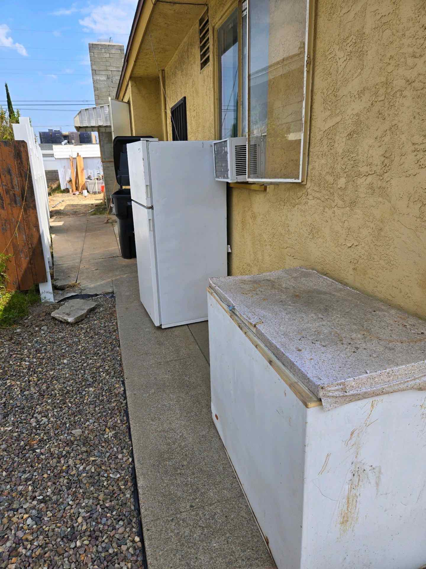 Old refrigerator, window AC unit, and chest freezer set out for JunkMD+ appliance removal in San Diego