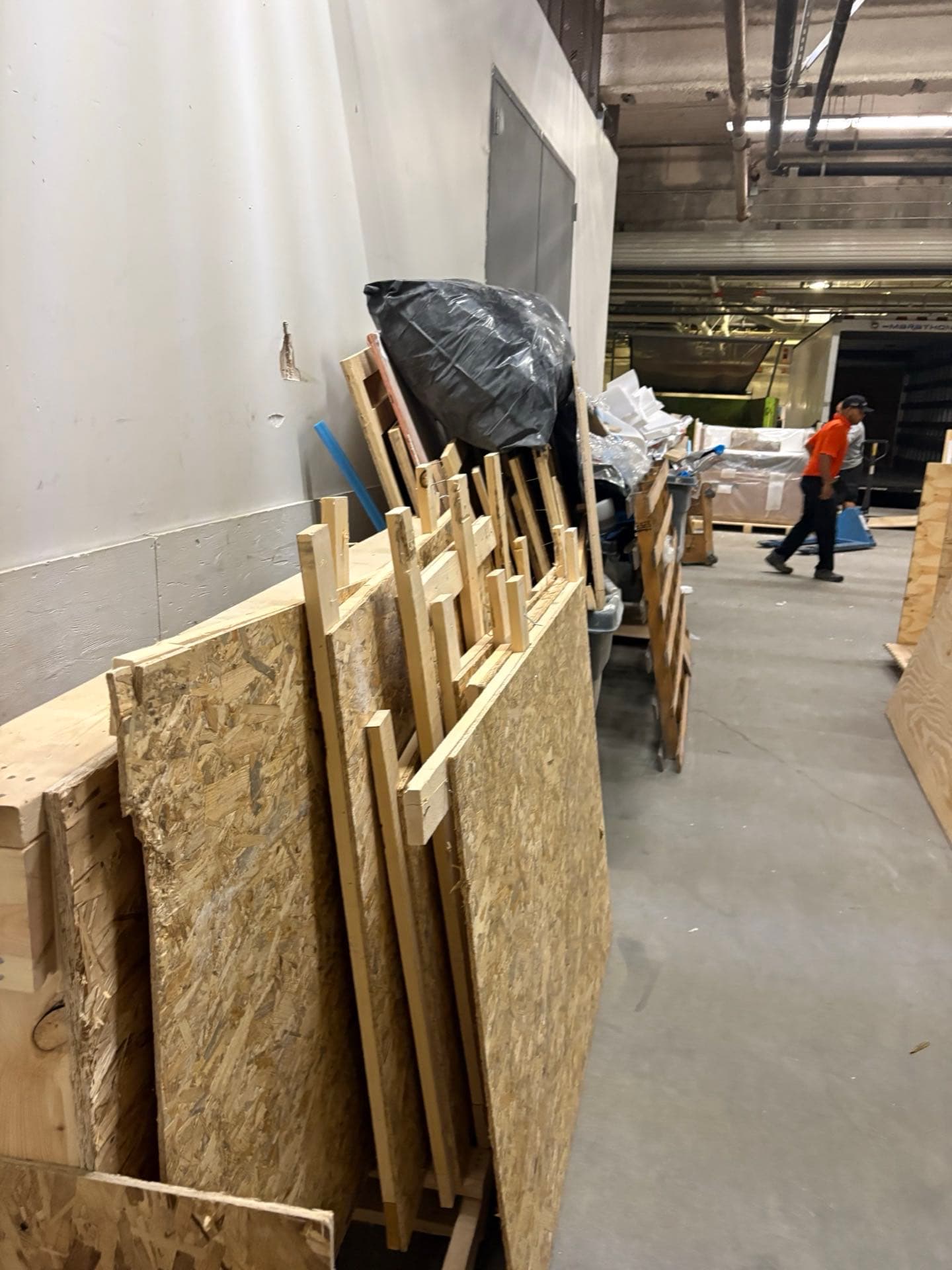 JunkMD+ crew member walking past stacked plywood crates on a San Diego construction debris job