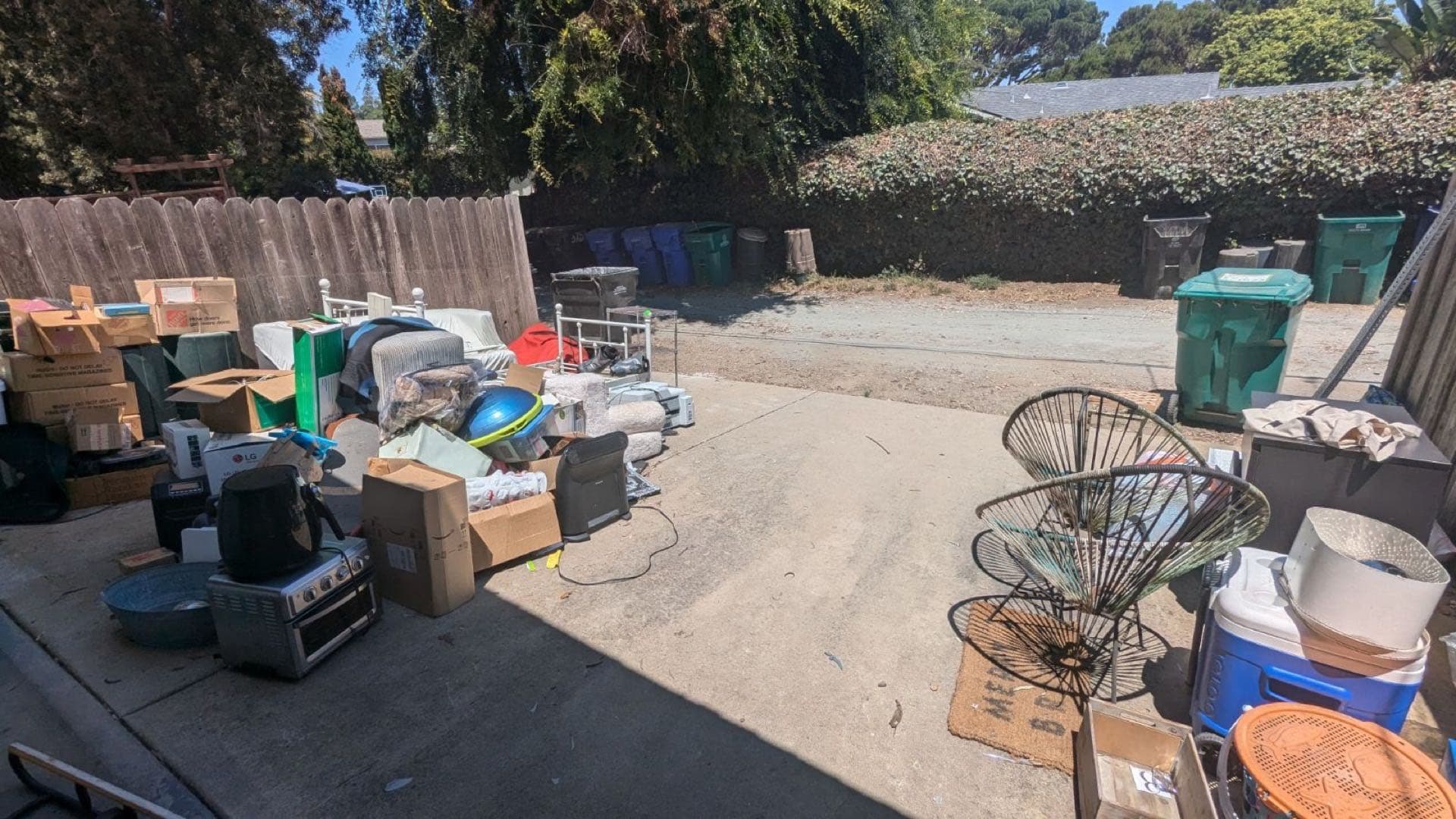 Driveway and garage cleanout in San Diego — boxes, electronics, chairs, and bins staged for JunkMD+ pickup