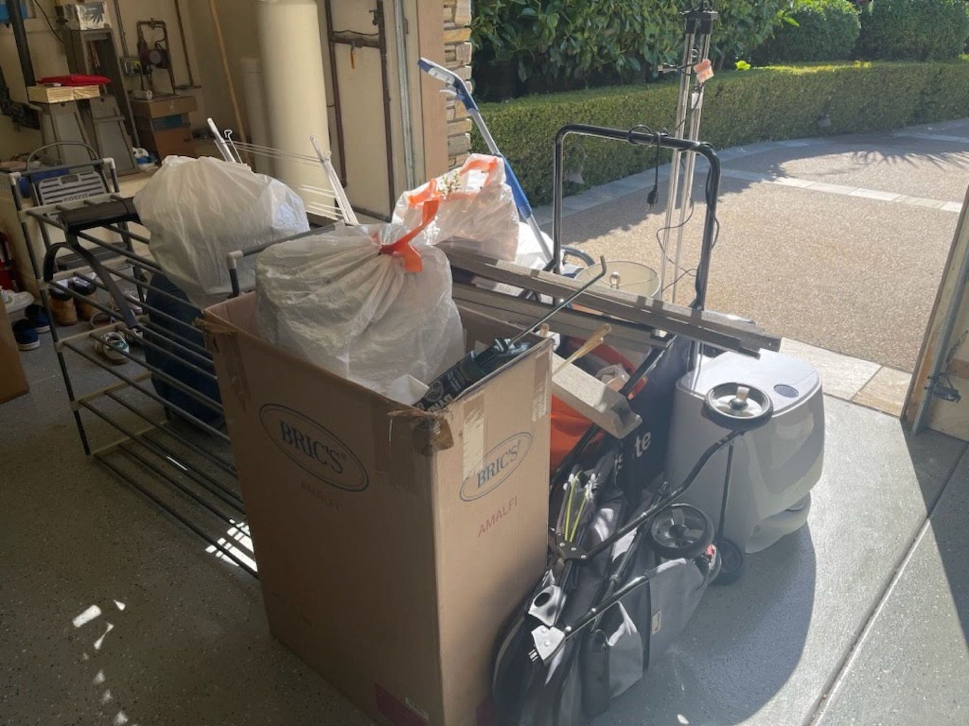 Garage cleanout pile — bags, boxes, and a walker prepped for JunkMD+ haul-away in San Diego