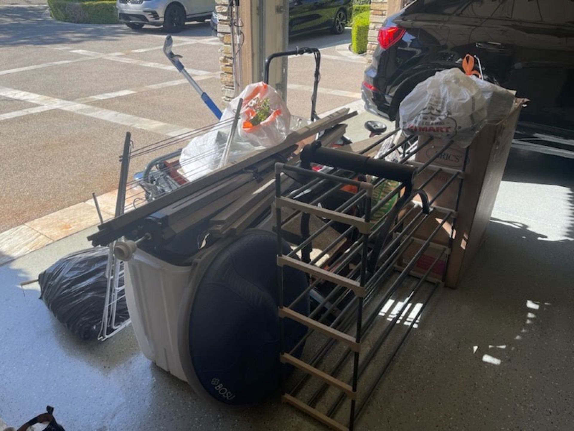 Driveway garage cleanout in San Diego — fitness equipment and shelving ready for JunkMD+