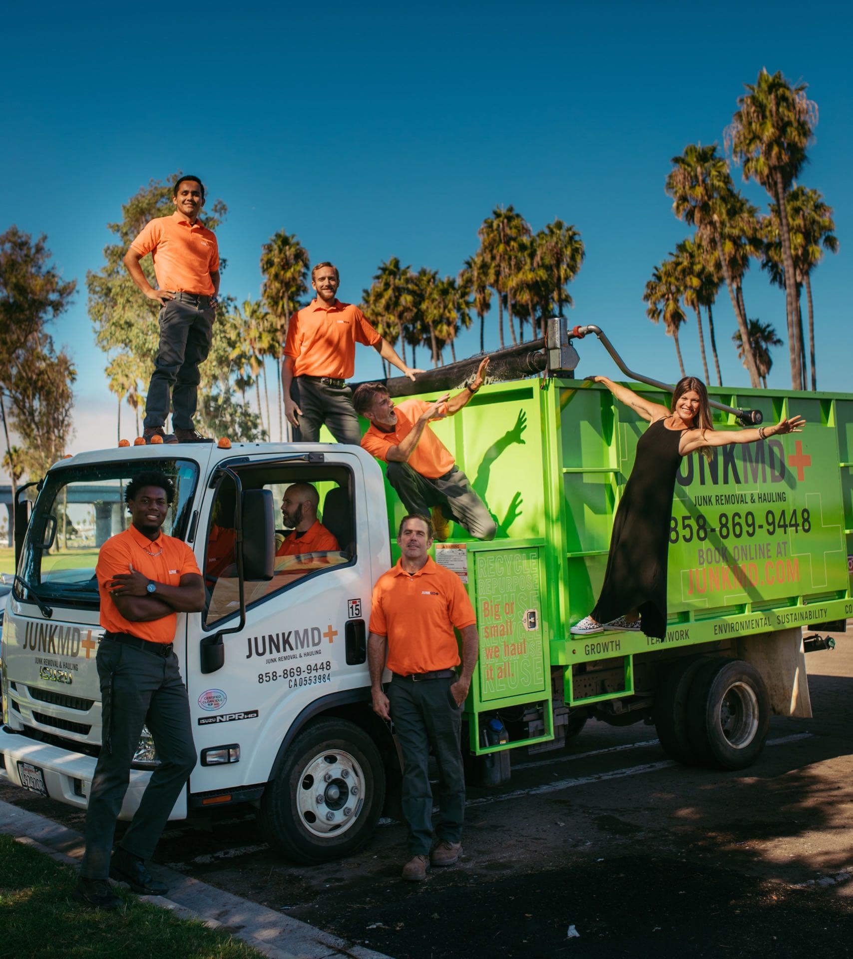 JunkMD+ owners and crew posed on and around the green truck under San Diego palm trees
