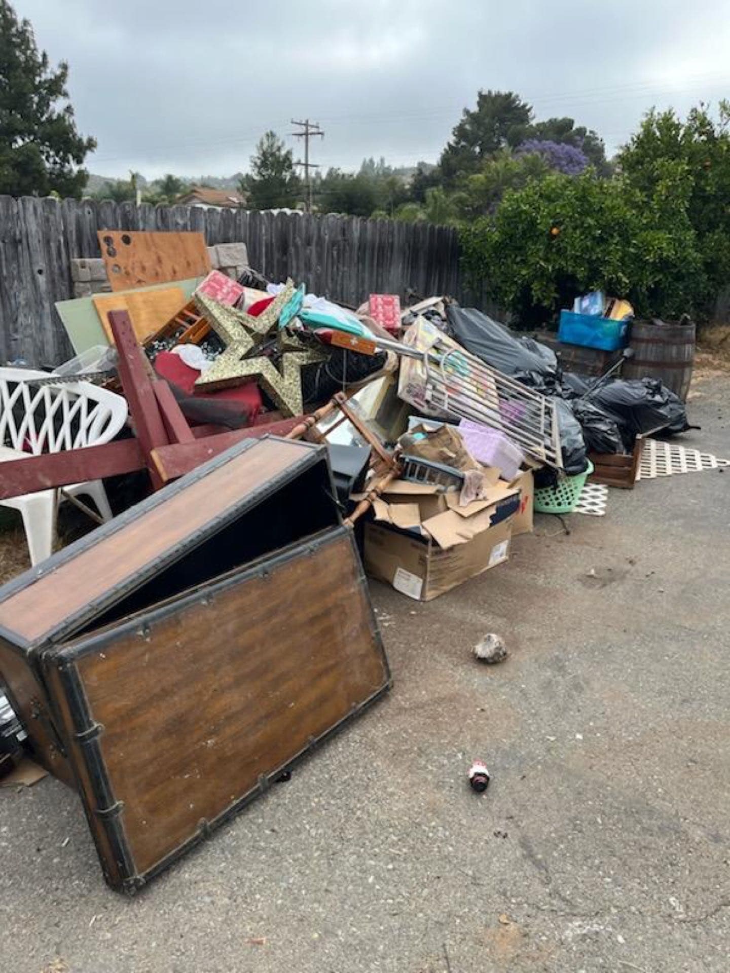 Yard waste pile at the curb — trunk, chairs, and bags ready for JunkMD+ haul-away in San Diego