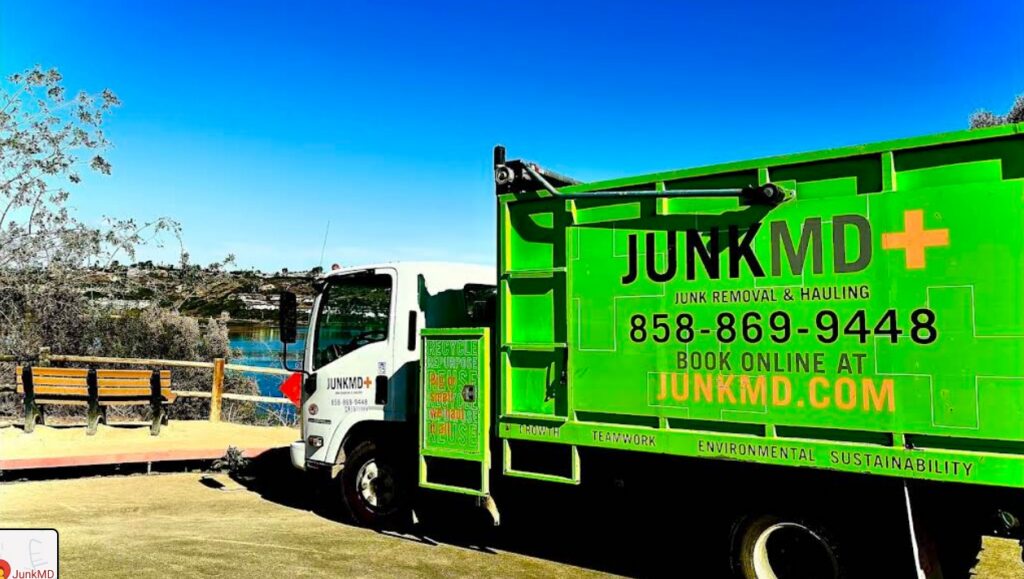 Bright green Junk MD junk removal and hauling truck parked at a scenic lookout point, promoting environmental sustainability.
